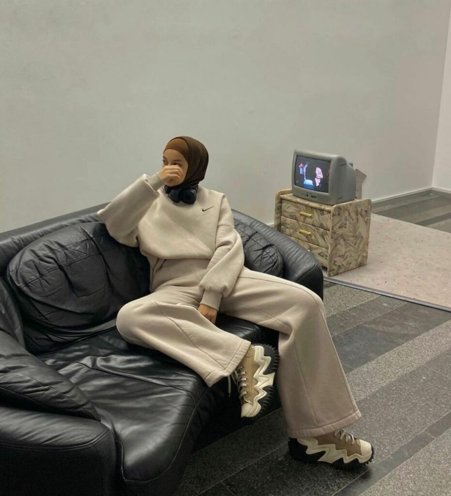 Besucherin in Hijab, Jogginganzug und Sneakern sitzt auf einem Sofa in der Arbeit "2000" in Kyiv, Ukraine